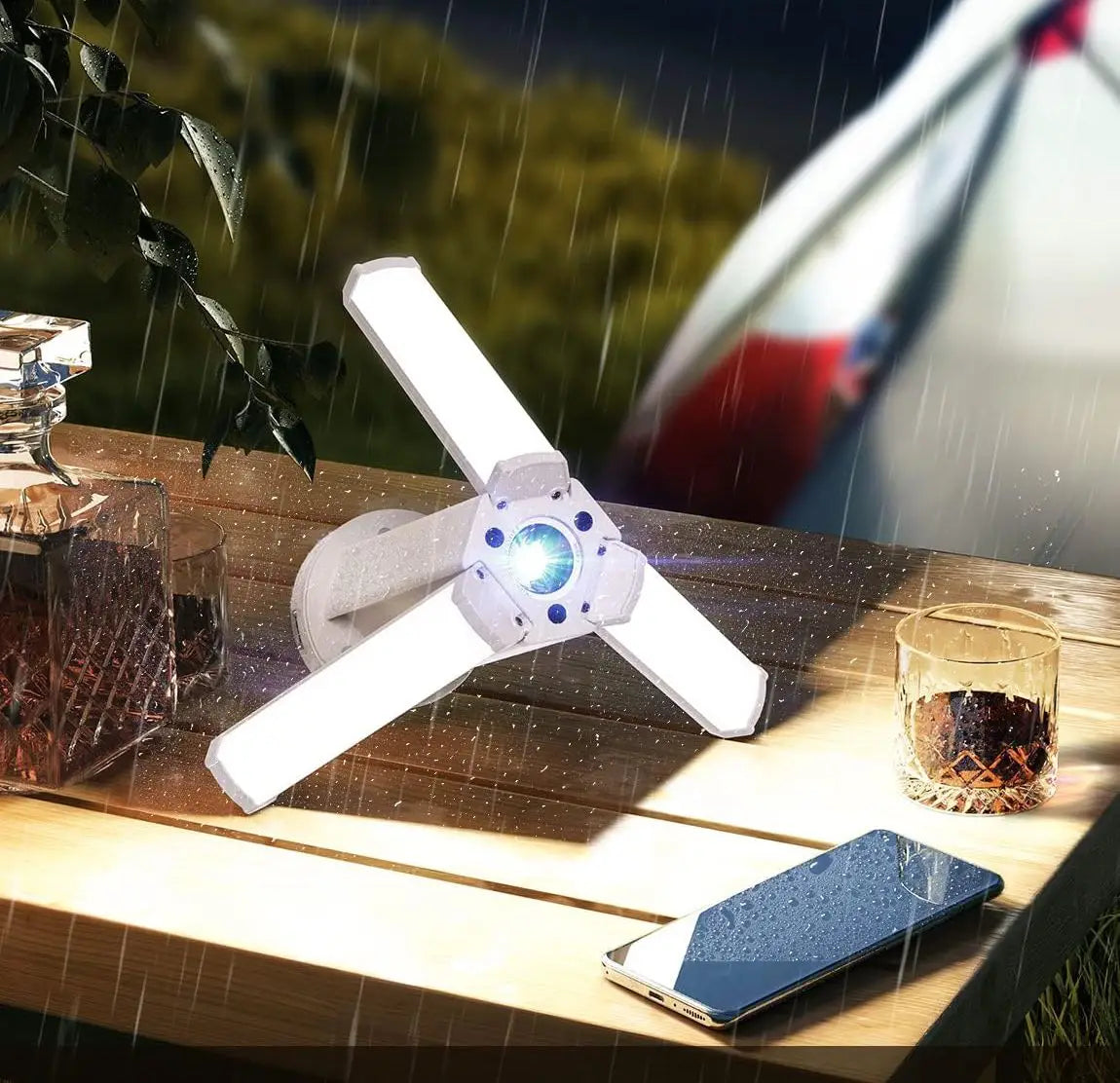 Сгъваема къмпинг лампа X6608 с три разгънати LED панела, поставена върху дървена маса по време на дъжд.